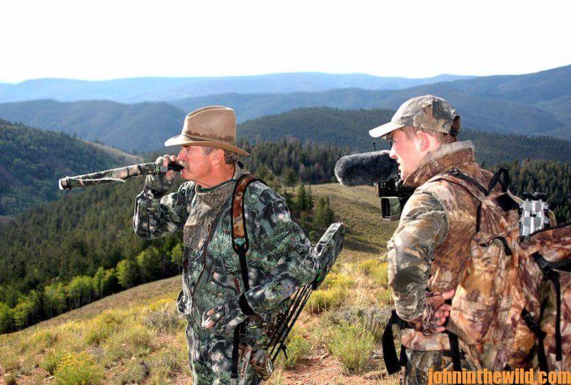 Two elk hunters in the field: one calling in an elk while the other records