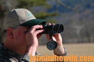 A hunter scouts out the area using binoculars
