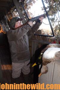 A hunter aims his rifle in the duck blind