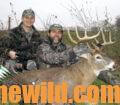 Two hunters pose with a downed deer
