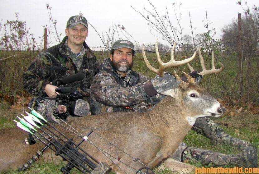Two hunters pose with a downed deer