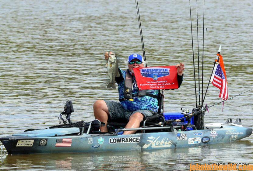 McElroy holds a bass and displays a tournament flag from his kayak