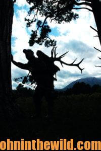 A silhouette of a hunter packing out an elk