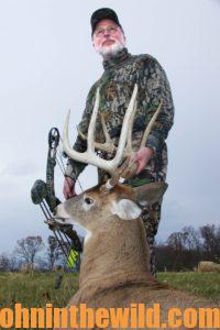 A hunter holding his downed deer by the antlers
