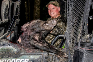 A hunter holding a downed pig