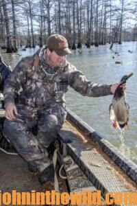 A hunter retrieves a downed duck from the water