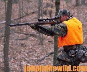 A hunter aims his rifle