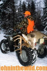 A hunter with his downed deer on the back of an ATV