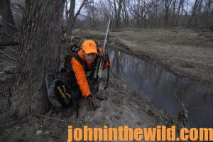 A hunter checks the deer tracks left near a stream