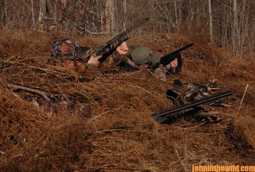 A group of hunters takes aim from their blind