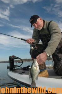 An angler reels in a crappie
