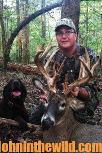 A hunter and his dog happily pose with a downed deer