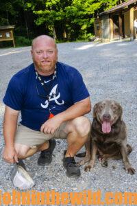 A hunter and his trailing dog smile for a photo