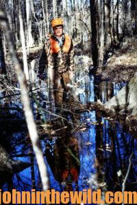 A hunter crosses a creek carrying the head of a deer