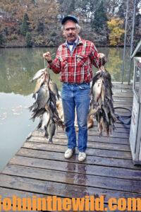 An angler holds two large catches of crappie - one for each hand