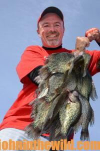 A fisherman holds a large catch of crappie