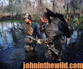 Two turkey hunters wade in a creek