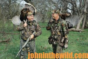 Two hunters talk while carrying their downed turkeys