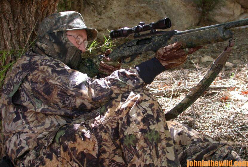 A hunter waits with aimed rifle for a gobbler
