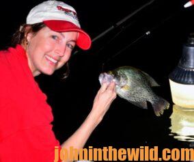 Woman poses with a crappie she caught while nighttime fishing