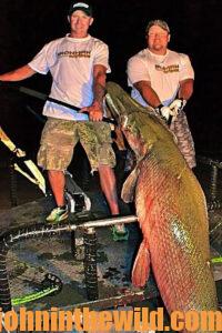 A couple bowfishermen show off their catch at night