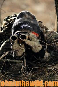 a hunter looks for deer through his binoculars