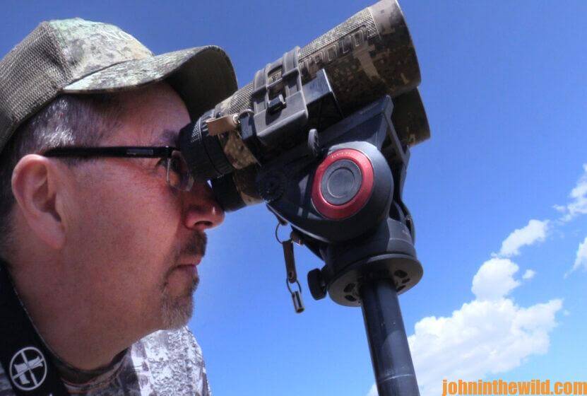 A hunter looks for deer through his binoculars
