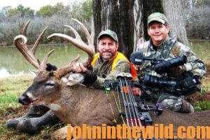 Two hunters pose with a downed deer