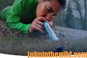 A woman uses the LifeStraw to drink from a stream