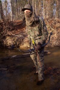 Bow deer hunter in a creek
