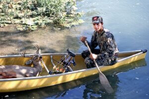 Deer hunter in a canoewith his trophies