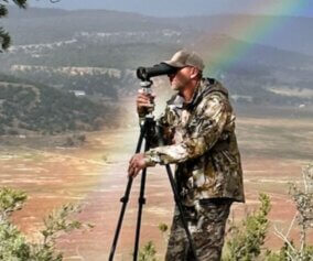 Hunting photographer with a rainbow background