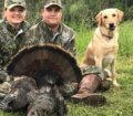 Two turkey hunters and their dog with their trophy turkey