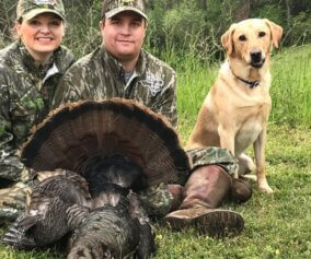 Two turkey hunters and their dog with their trophy turkey